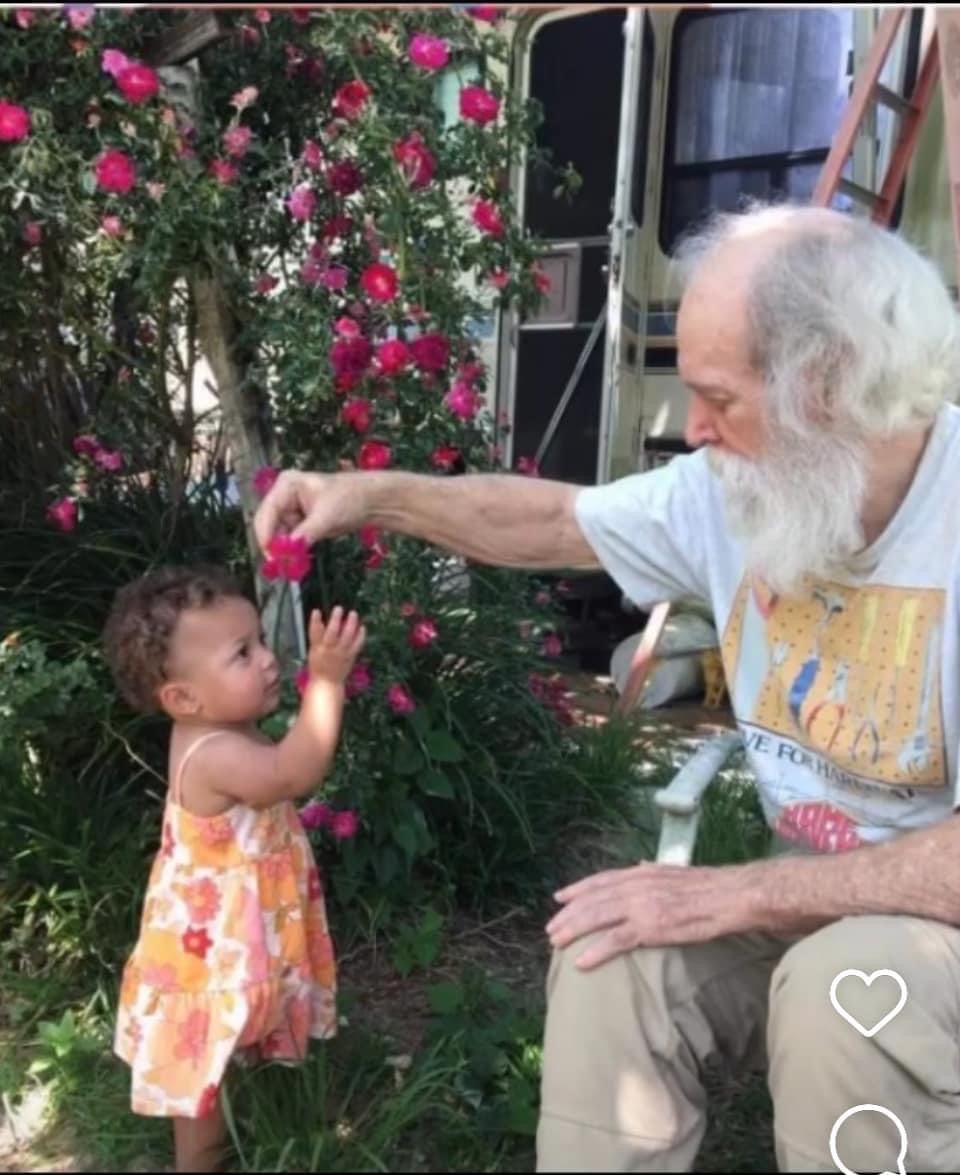 Teaching his great grand daughter to love flowers & to pick berries