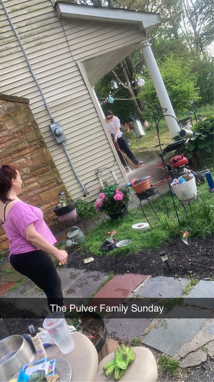 Amanda pressure washing the porch, because she wanted to decorate it. (June, 2024)
